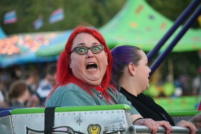 Close-up of young woman with carousel in amusement park