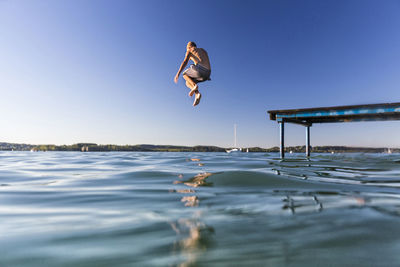 Man jumping in water against clear sky
