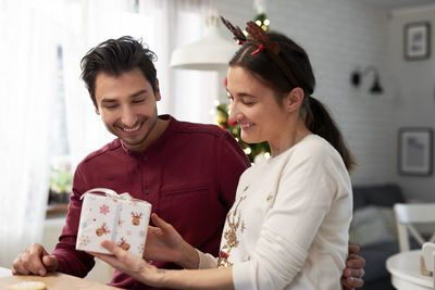 Happy couple holding christmas presents at home