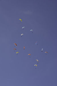 Low angle view of kites flying against clear blue sky