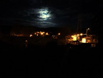 Silhouette of illuminated lights against sky at night