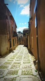 Cobblestone street amidst buildings against sky