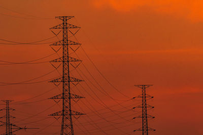 Low angle view of silhouette electricity pylon against romantic sky