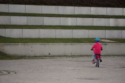 Rear view of man riding bicycle on road