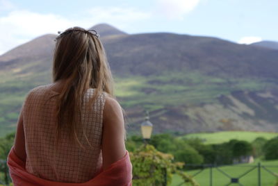 Rear view of woman standing on mountain against sky