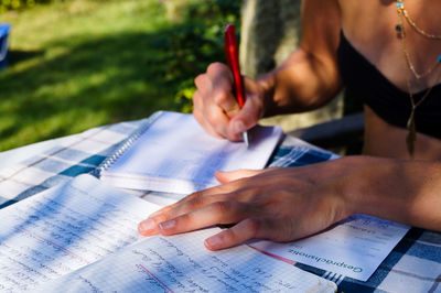 Cropped image of woman writing in book on table