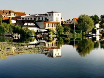 Buildings by lake against sky in city