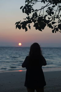 Silhouette woman looking at sea during sunset
