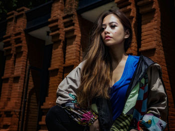 Portrait of young woman standing against wall