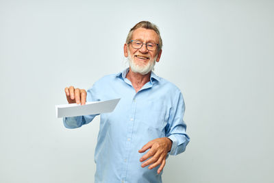 Portrait of man holding paper currency against white background