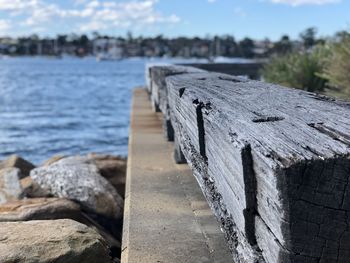 Close-up of wooden post on pier by sea against sky
