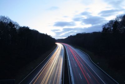 Light trails on road against sky at night