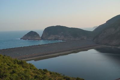 Scenic view of sea and mountains against clear sky