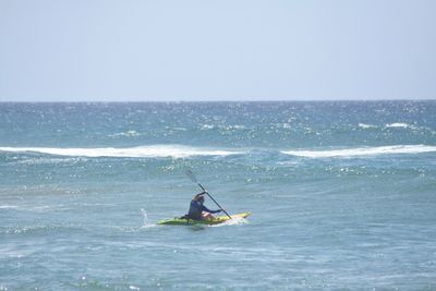 Man surfing in sea against clear sky