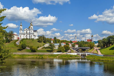 Built structure by river and buildings against sky