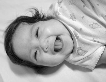 Portrait of cheerful baby lying on bed