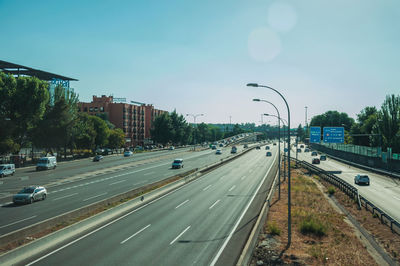 Vehicles on road against sky in city