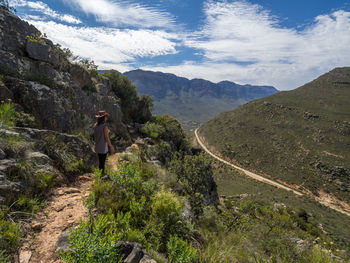 Rear view of woman walking on mountain against sky