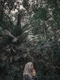 Portrait of woman standing by tree in forest