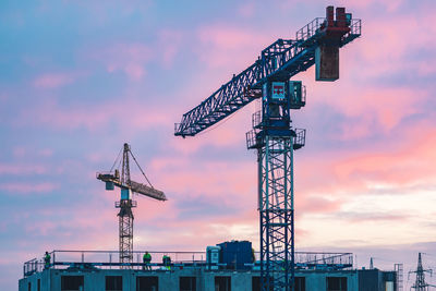 Worksite with cranes, new buildings or houses under construction with workers with helmet at work