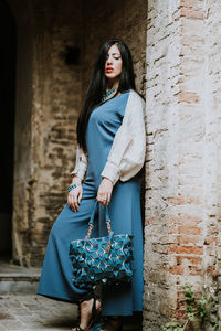 Portrait of young woman standing against wall