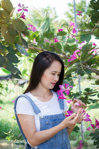 Beautiful young woman standing by flowering plants