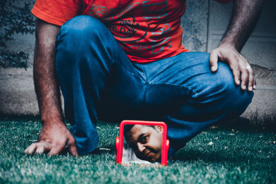 Low section of man crouching by mirror with reflection