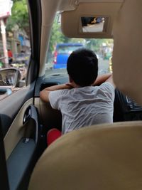 Rear view of boy sitting in car