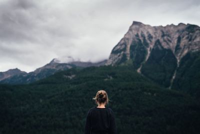 Rear view of woman standing on mountain against sky