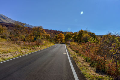 Road amidst trees against sky during autumn