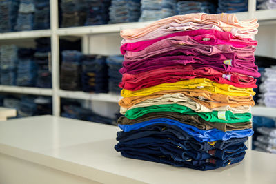 Multi colored stacked jeans on table in store