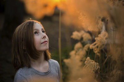 Girl looking up while standing by plants