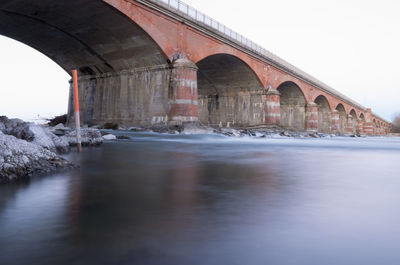 Arch bridge over river against clear sky