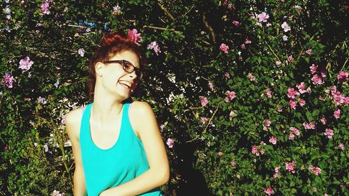 Happy woman looking away while standing against flowering tree on sunny day