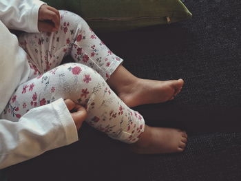 Low section of baby girl sitting on sofa at home