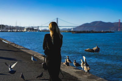 Rear view of woman by sea against sky