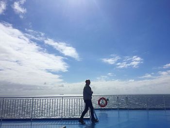 Man standing on railing against sea