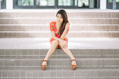 Full length portrait of woman sitting on staircase