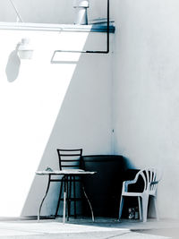 Empty chairs and table against wall