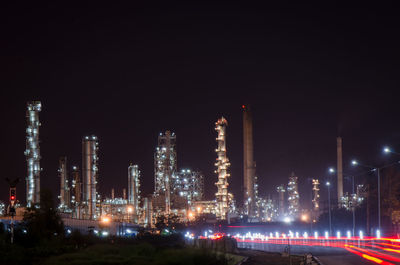 Illuminated factory against sky at night