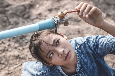 Girl looking at tap on drought field