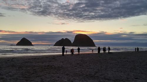 Silhouette of beach against cloudy sky