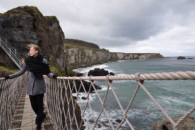 Woman standing on footbridge over sea