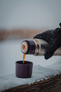 Drinking hot tea from a thermos against the view in the snowfall