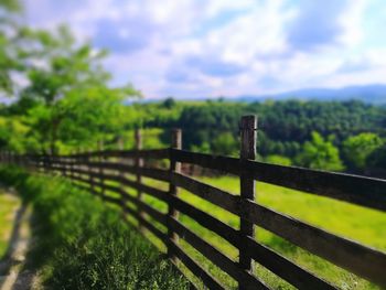 Close-up of railing on landscape against sky