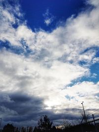 Low angle view of trees against cloudy sky