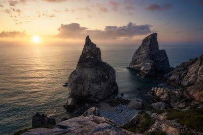 Rocks on shore against sky during sunset