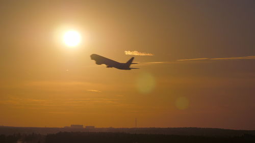 Silhouette bird flying against sky during sunset