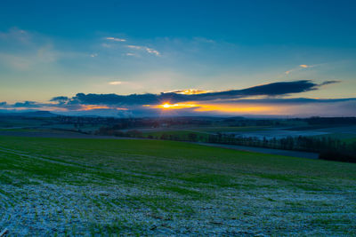 Scenic view of agricultural field against sky during sunset