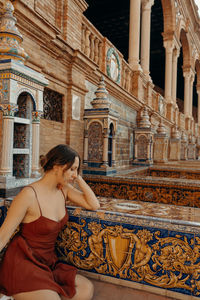 Side view of woman sitting on a building in seville. plaza de espana - spain square